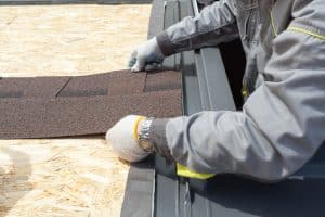 worker lays asphalt sheet